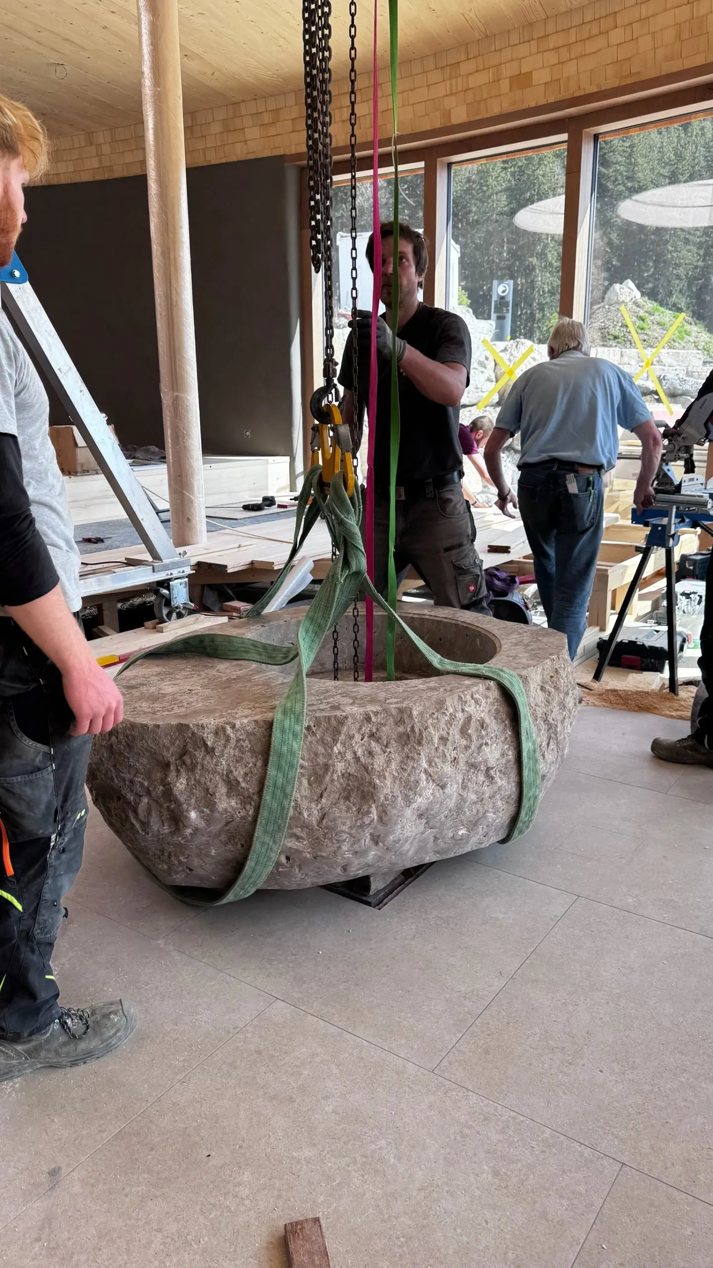 Einbau eines massiven Natursteinelements per Kran auf der Baustelle