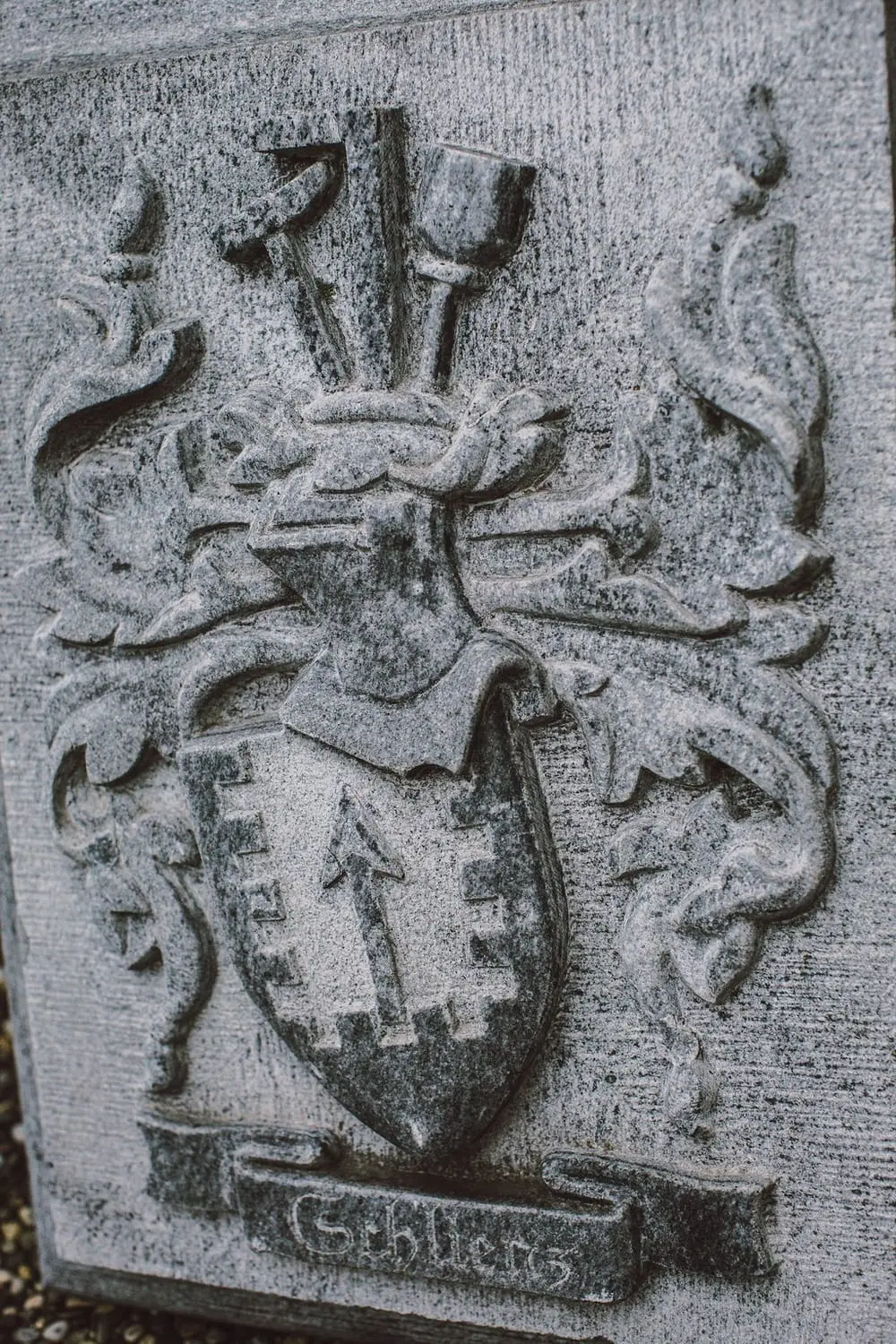 In Stein gehauenes Wappenrelief mit dem Namen Schlienz und Steinmetzwerkzeug