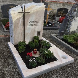 Felsen-Grabstein aus hellem Kalkstein mit naturbelassener Oberfläche und horizontal integriertem Metallkreuz