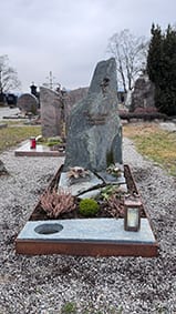 Grau-grüner Naturstein-Felsstein mit goldenem Sonnenmotiv und rötlicher Porphyr-Einfassung – STOI Steinmetzwerkstatt