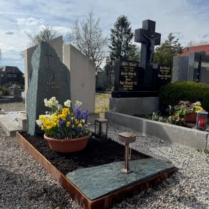 Grabstein aus dunkelgrünem Gneis mit Kreuz und Felsblock in Corten-Stahl-Rosteinfassung