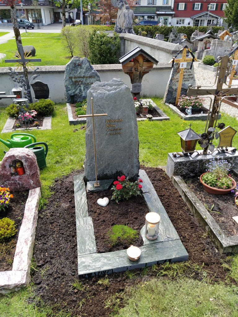 Naturbelassener dunkelgrüner Diabas-Felsstein mit Goldkreuz auf dem Friedhof – STOI Steinmetzwerkstatt