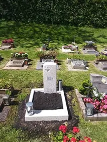 Urnenstele aus Kalkstein mit eingearbeitetem Kreuzrelief und naturbelassener Oberfläche
