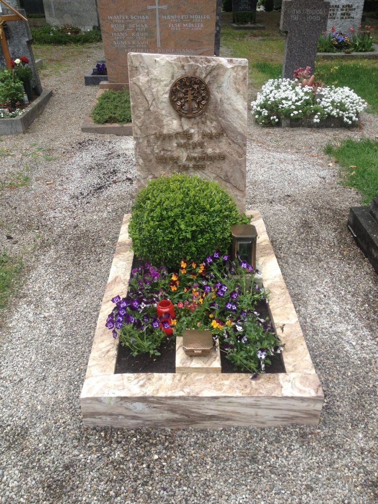 Grabstein aus hellem Naturstein mit klassischer Stelenform und großem runden Bronzemedaillon