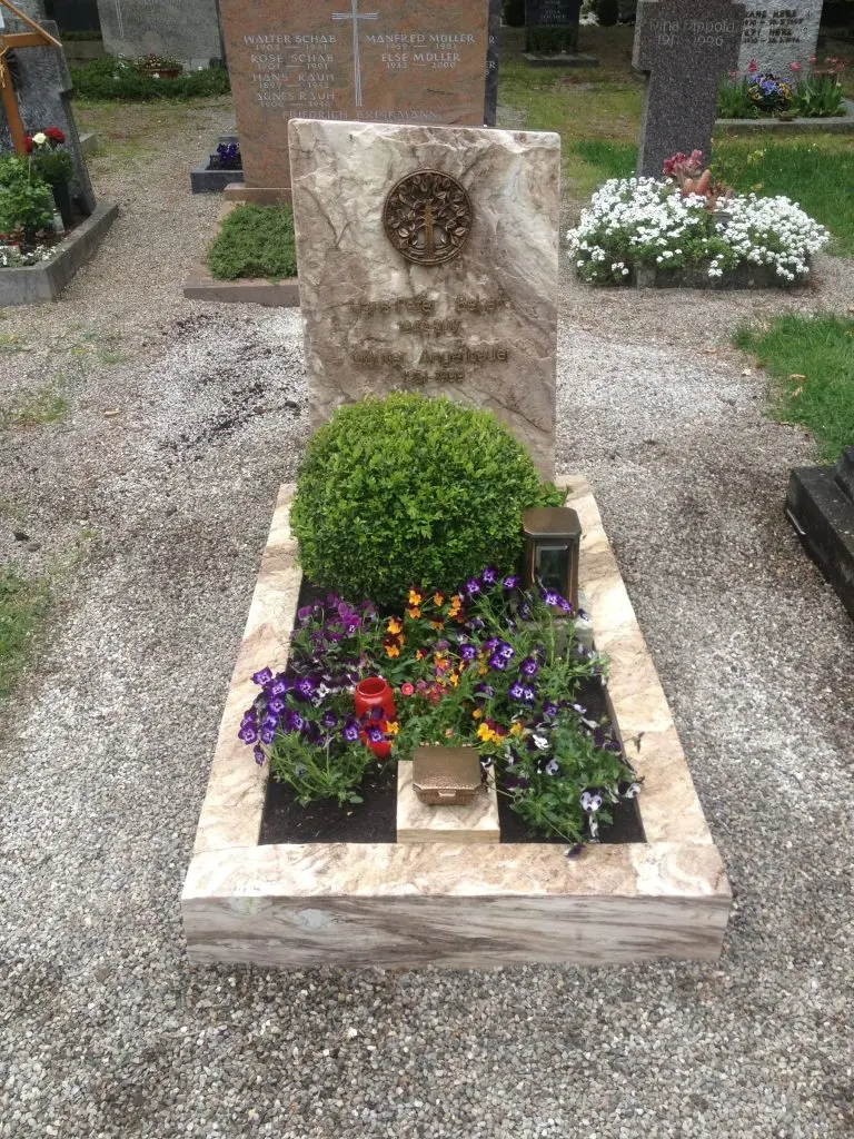 Grabstein aus hellem Naturstein mit klassischer Stelenform und großem runden Bronzemedaillon
