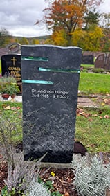 Dunkler Spaltbruch-Grabstein mit horizontal eingelassenen türkisfarbenen Glasscheiben von STOI Steinmetzwerkstatt