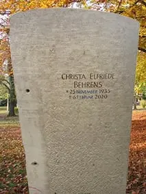 Schlanker Grabstein aus hellem Kalkstein mit sanft geschwungenem Rundbogen-Abschluss und feiner Schriftgravur