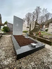 Schlichter zweiteiliger Grabstein aus dunklem Granit mit polierter Oberfläche und schrägem Abschluss