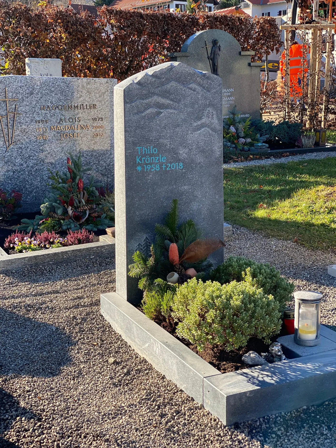 Dunkelgrauer Naturstein-Grabstein mit handwerklich eingearbeitetem Bergpanorama-Relief und organischer Felsform – Ansicht 2