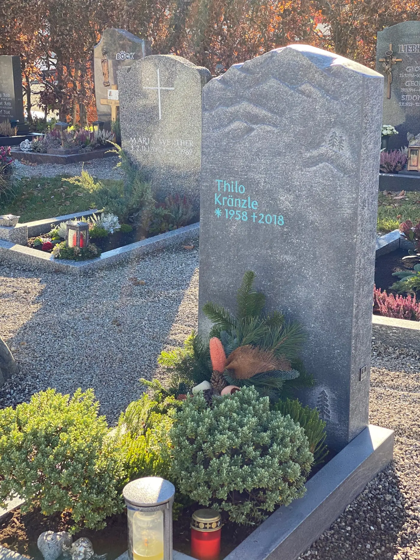 Dunkelgrauer Naturstein-Grabstein mit handwerklich eingearbeitetem Bergpanorama-Relief und organischer Felsform – Ansicht 3