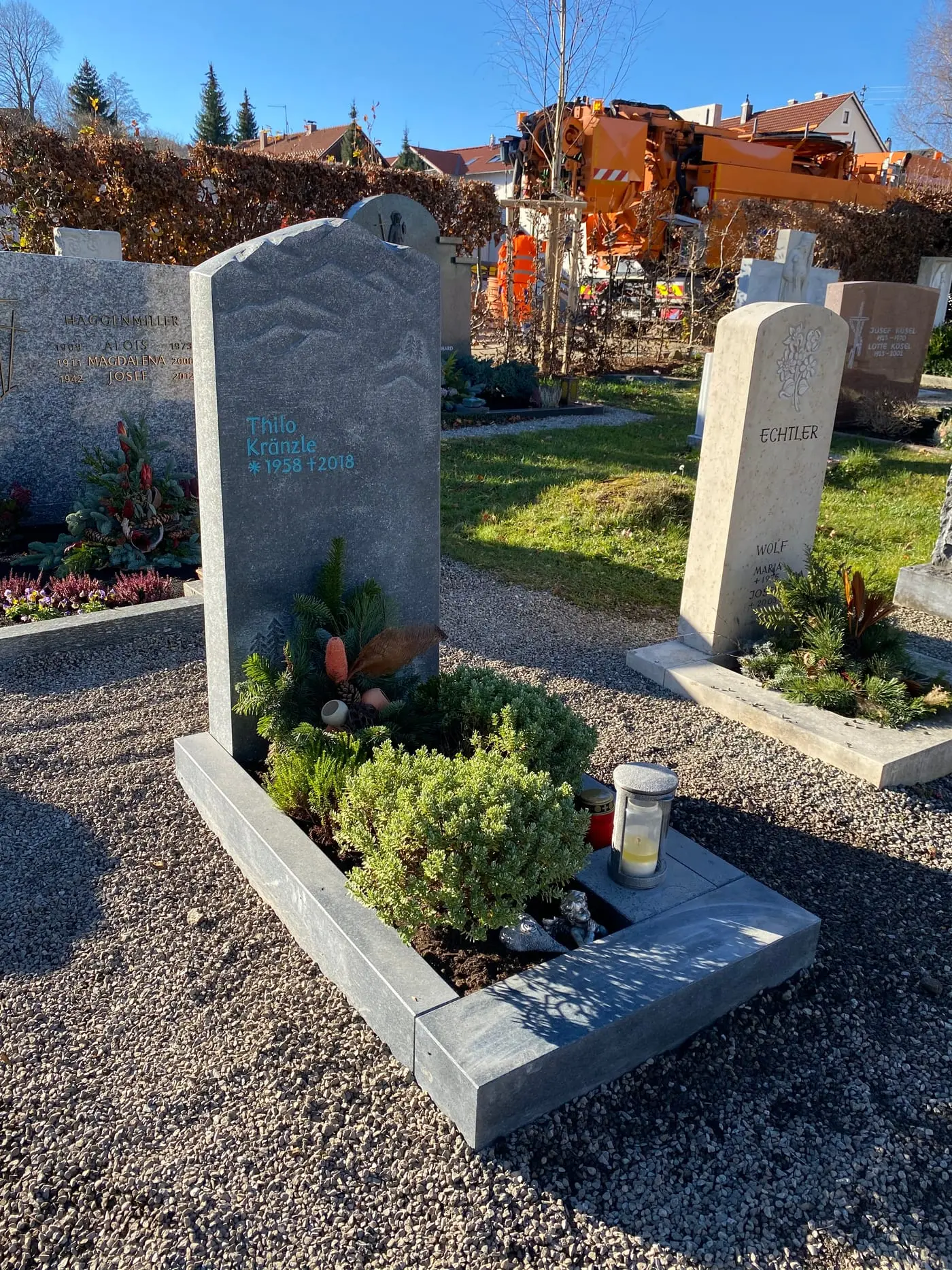 Dunkelgrauer Naturstein-Grabstein mit handwerklich eingearbeitetem Bergpanorama-Relief und organischer Felsform – Ansicht 4