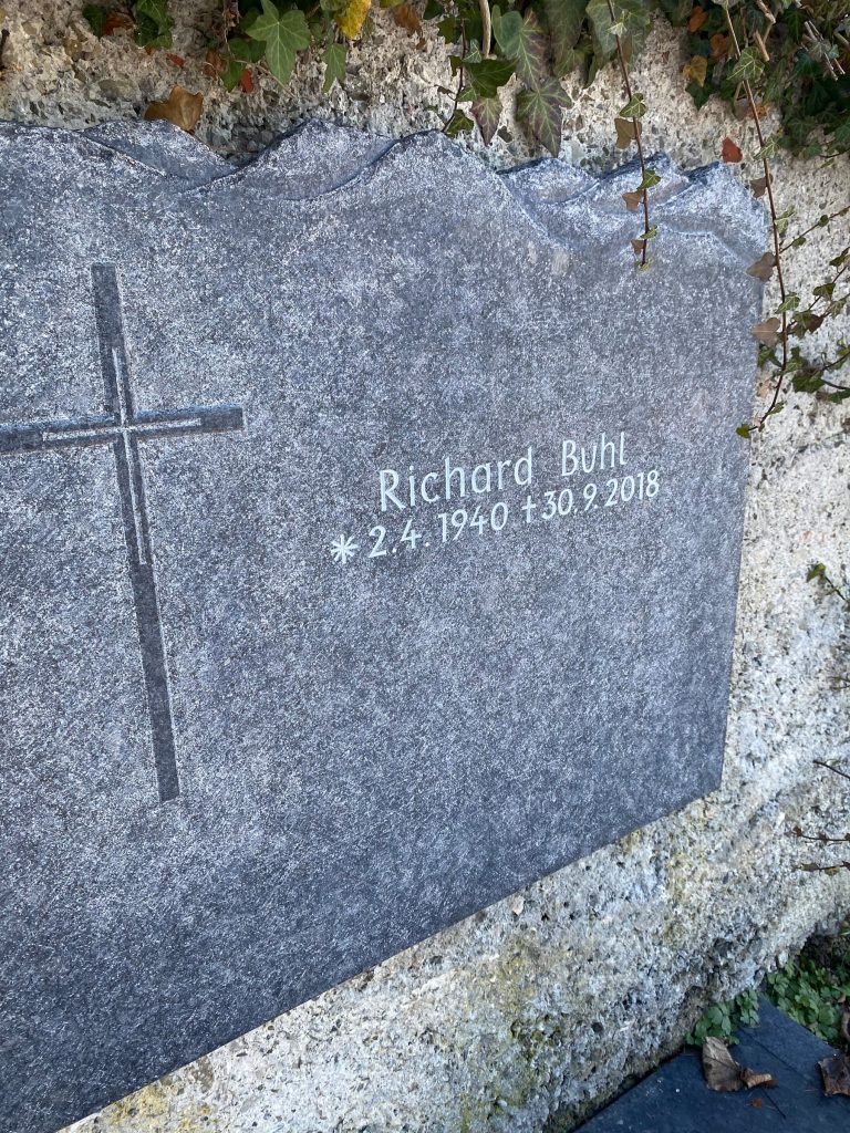 Anthrazit-Granit Wandgrabstein mit unregelmäßiger Bruchkante und passendem dunklen Liegestein