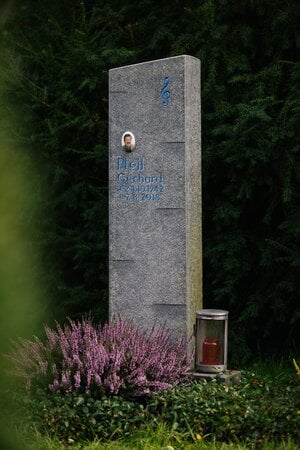 Schlanke Granit-Stele mit blau graviertem Violinschlüssel und runder Fotoplakette für Musikliebhaber