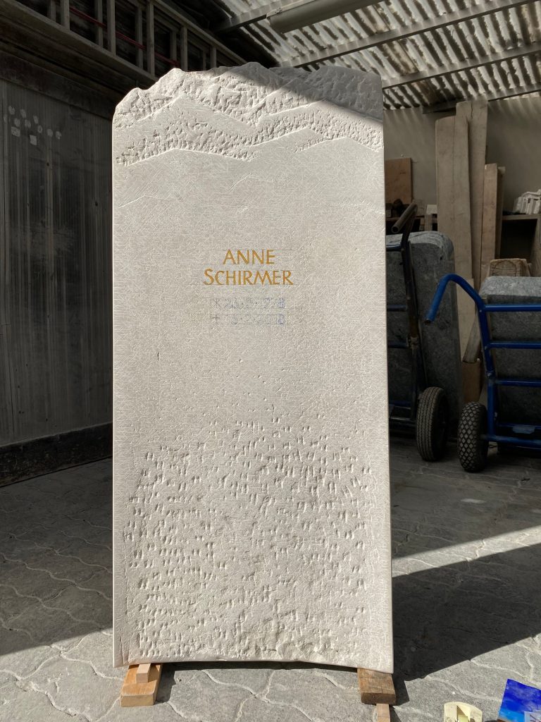 Helle schlanke Kalkstein-Stele mit Bergsilhouette als geschwungenem Abschluss von STOI Steinmetzwerkstatt