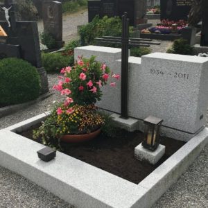 Helle Granit-Grabanlage mit zwei kubischen Steinelementen und schlankem elegantem Metallkreuz