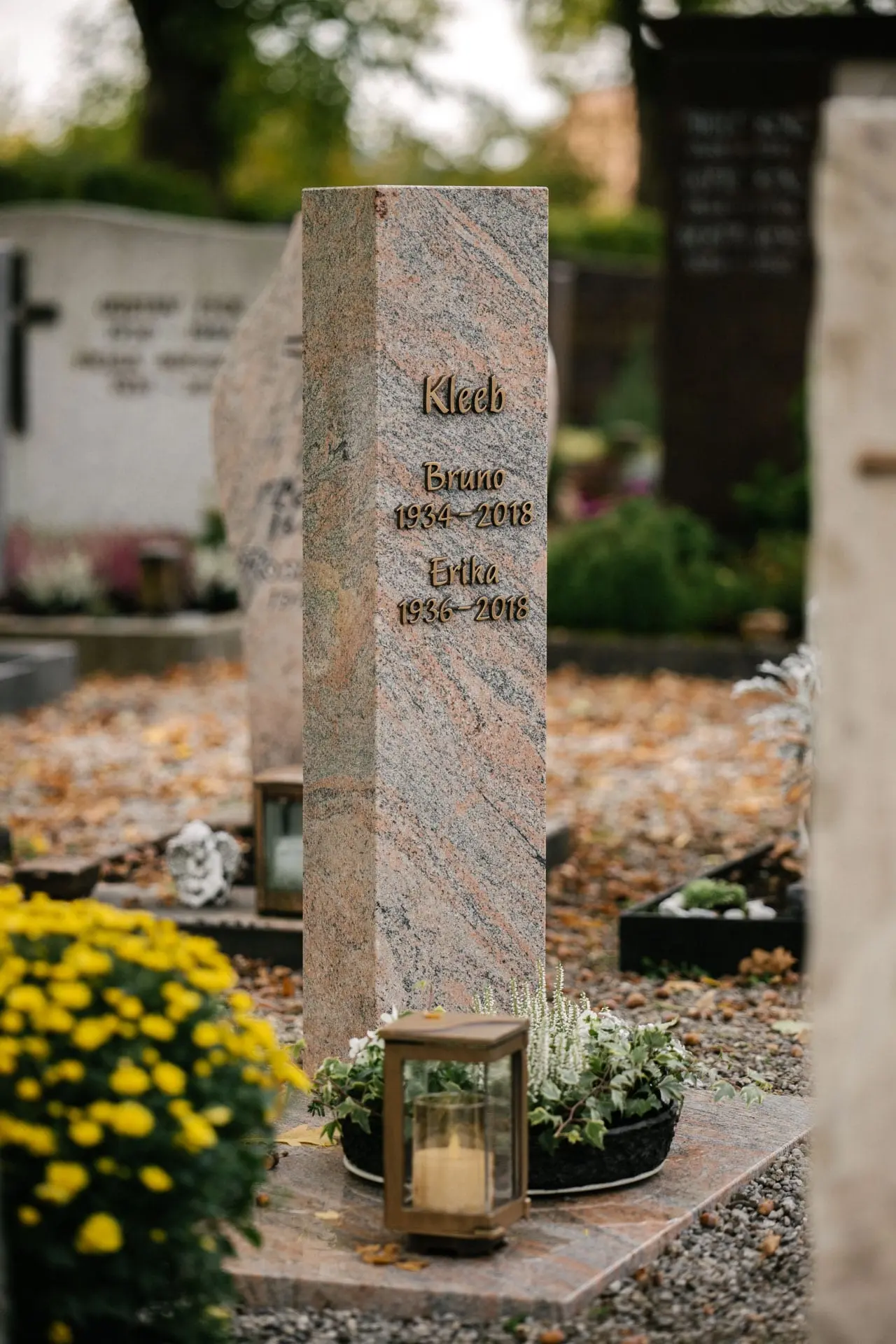 Hohe polierte Granit-Stele mit farbiger Maserung in Rosa und Grau sowie Bronzeschrift von STOI