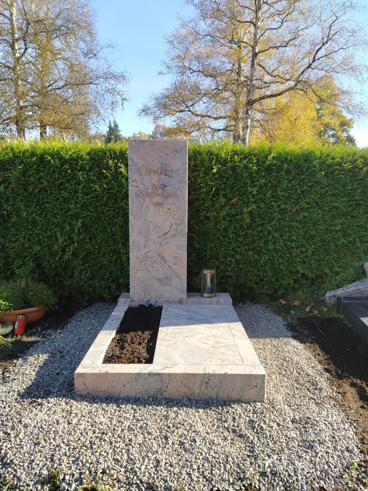 Handwerklicher Kreuzgrabstein aus hellem Kalkstein mit floralen Reliefmotiven und organischer Steinstruktur – Ansicht 2