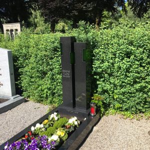 Schwarzer Granit-Grabstein mit zwei integrierten grünen Glas-Elementen und heller Schriftgravur
