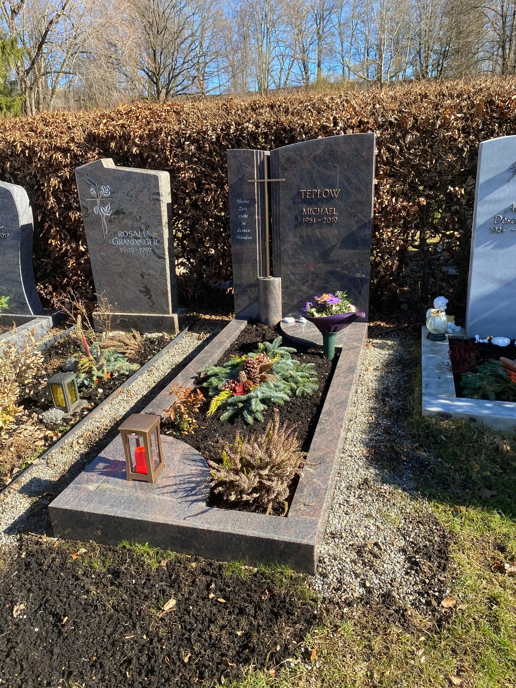 Polierter Schwarzgranit-Grabstein mit schlankem goldenem Metallkreuz und tiefglänzender Oberfläche