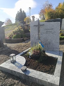 Hellgrauer Granit-Grabstein mit aufgesetztem Metallkreuz und zweiteiliger Grabeinfassung von STOI Steinmetzwerkstatt
