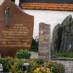 Schlanke polierte Granit-Stele in Rot neben bestehendem Familiengrabstein auf historischem Friedhof