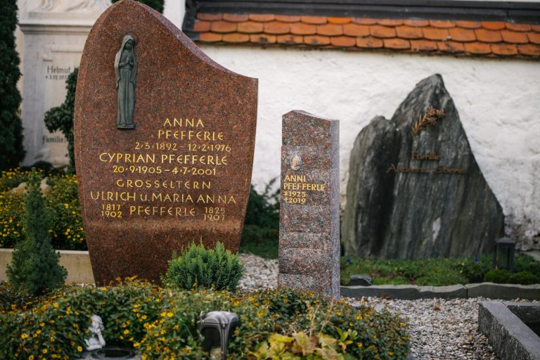Schlanke polierte Granit-Stele in Rot neben bestehendem Familiengrabstein auf historischem Friedhof