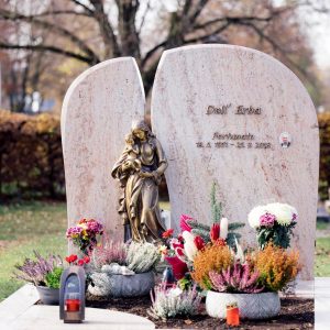 Zweiteiliger Grabstein aus rosafarbenem Kalkstein mit Rundbogen-Form und Bronzemadonna in der Mitte
