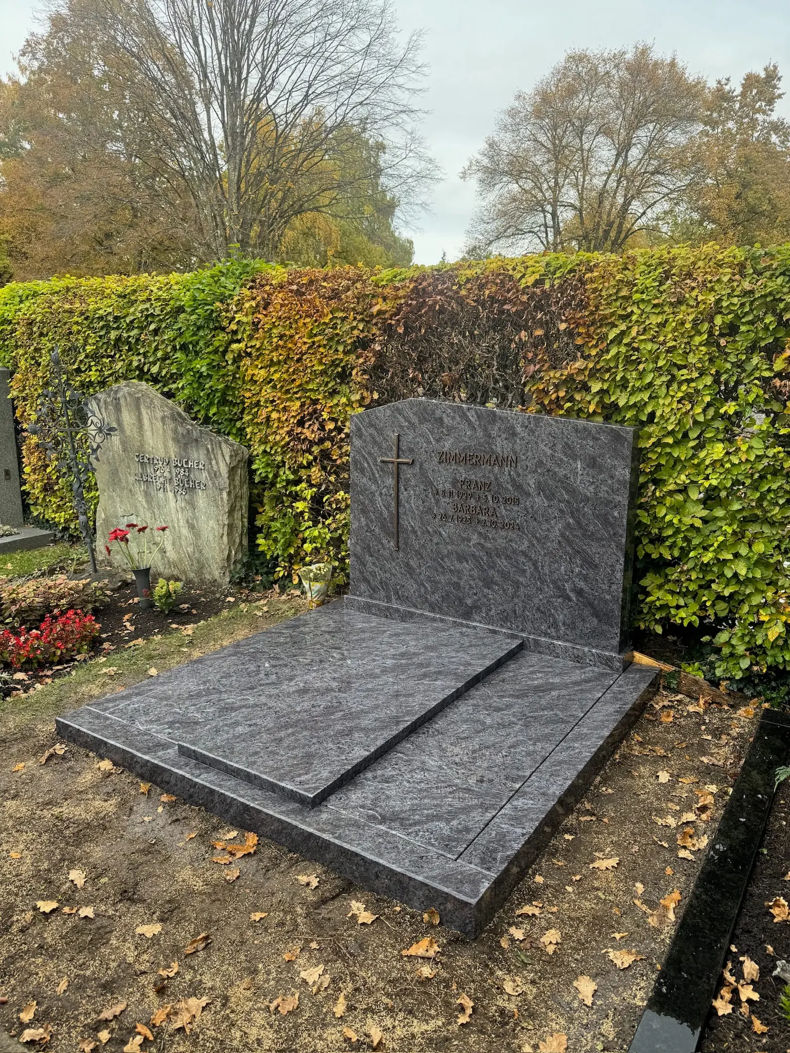 Anthrazit-Granit-Doppelgrabstein mit polierter Oberfläche und flacher Grabeinfassung von STOI Steinmetzwerkstatt