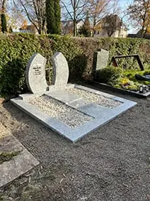 Zweiteiliger Doppelgrabstein aus hellem poliertem Naturstein mit gerundeten Bögen und Hochglanzoberfläche