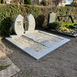 Zweiteiliger Doppelgrabstein aus hellem poliertem Naturstein mit gerundeten Bögen und Hochglanzoberfläche