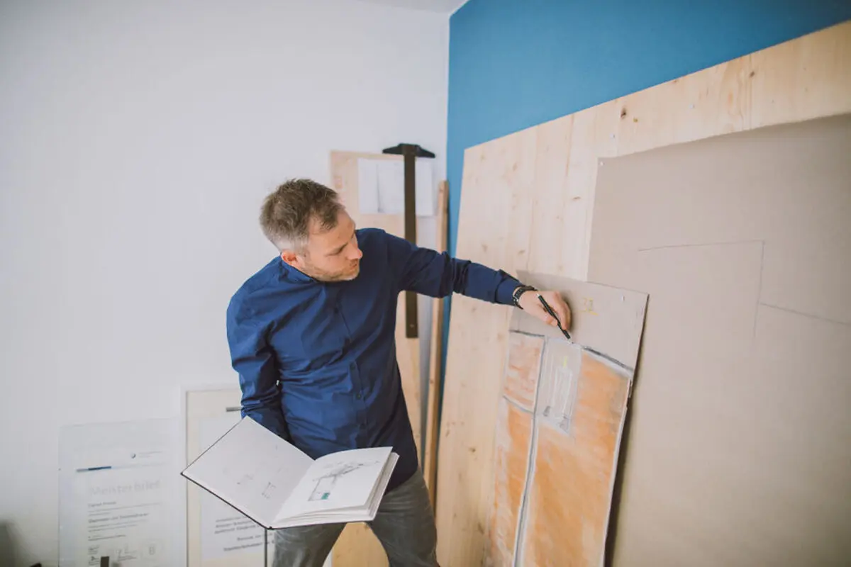 Steinmetzmeister zeichnet einen Grabmal-Entwurf an der Wand
