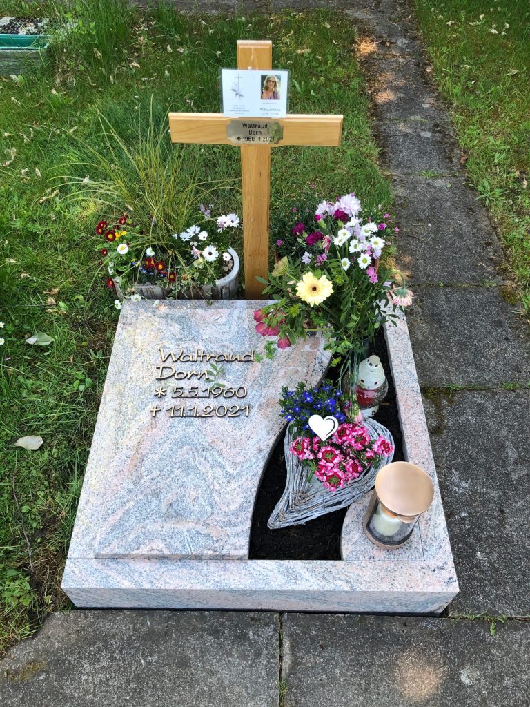 Urnengrab-Liegestein aus rosa Granit in Wellenform mit polierter dunkler Einlagetafel für die Inschrift