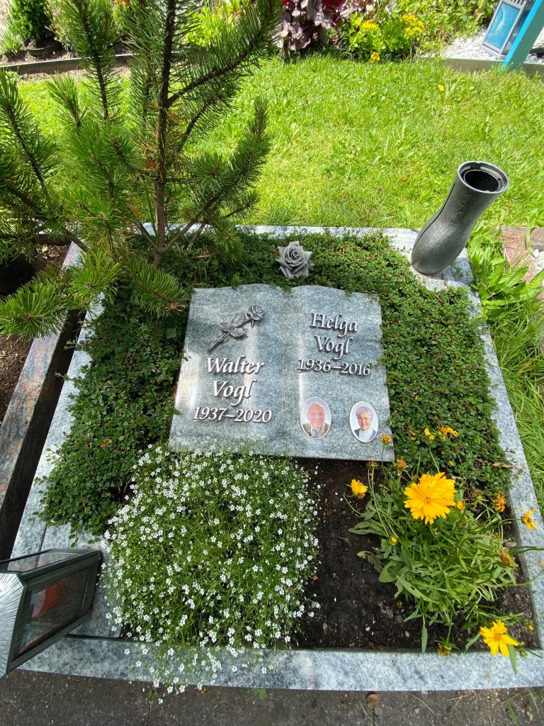 Buchförmiger Liegestein aus Blaugranit mit zwei Porträtmedaillons und Bronzerose von STOI