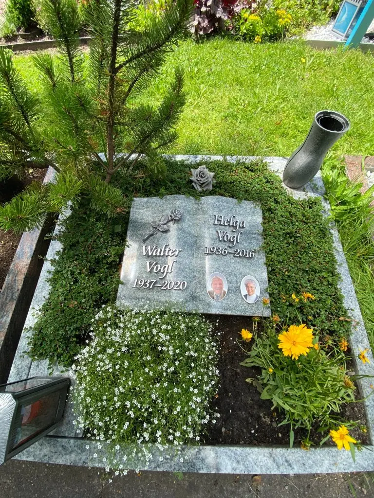 Buchförmiger Liegestein aus Blaugranit mit zwei Porträtmedaillons und Bronzerose von STOI