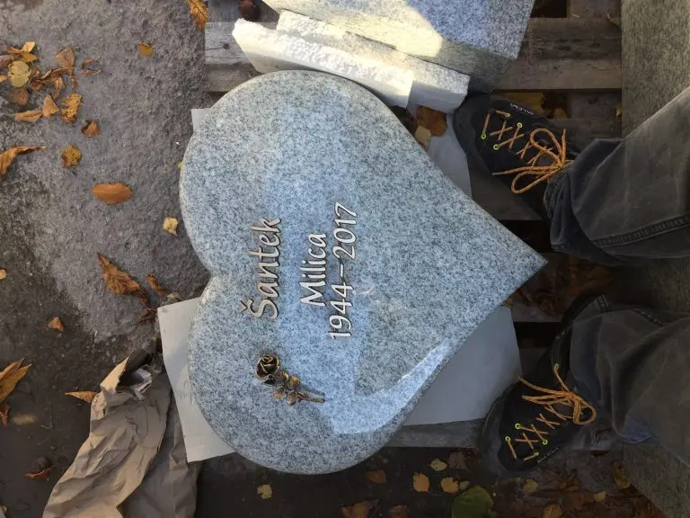 U 534 | Herzförmiger Urnengrabstein aus hellem Granit mit Bronzerose