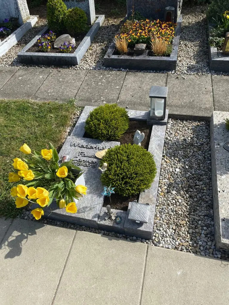Urnengrab-Liegestein aus anthrazitfarbenem Granit mit Steinrahmung von STOI Steinmetzwerkstatt