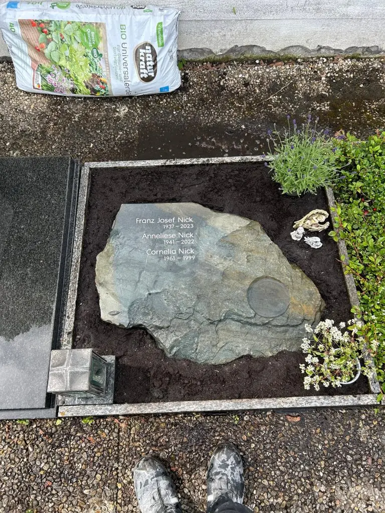 Natürlich geformter Fels-Liegestein aus grün-grauem Naturstein, flach liegend als Urnengrabstein