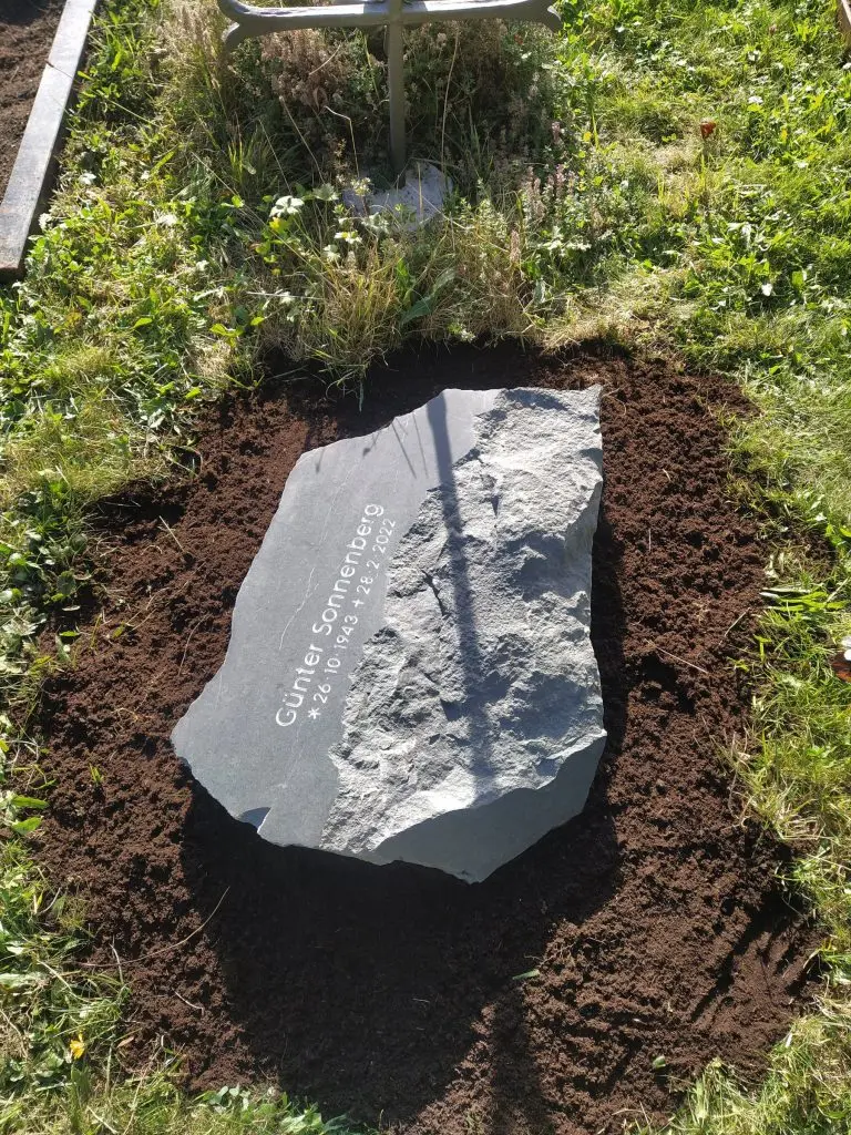 Liegender Felsen-Grabstein aus dunklem Gneis mit organischer Naturform für Urnengrab von STOI